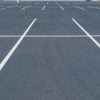 Pavimento asfáltico para un aparcamiento señalizado con las líneas de delimitación de plazas.